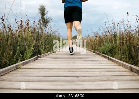 Rückansicht eines männlichen Jogger laufen auf einem Holzsteg Stockfoto