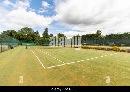 Grüne Tennisplatz mit Sport net und einzelne Linie Markierungen gegen bewölkter Himmel Stockfoto