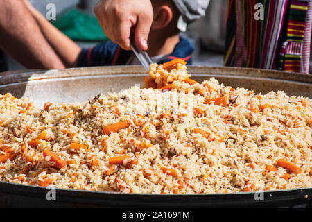 Echte traditionelle Straße pilav oder Plov, reisgericht Kochen im Lager oder Brühe, Hinzufügen von Gewürzen und anderen Zutaten wie Gemüse oder Fleisch Stockfoto