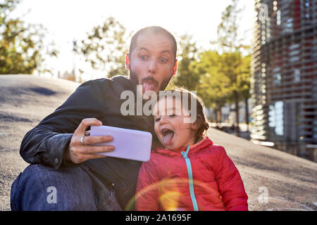 2-jähriges Mädchen und Vater selfies und Grimassen an einem Wintertag bei Sonnenuntergang, Barcelona, Spanien Stockfoto