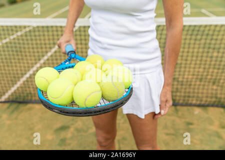 Weibliche Tennisspieler Holding einen Tennisschläger mit Kugeln auf Gras Hof Stockfoto