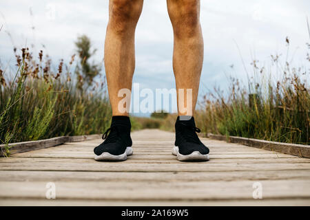 Schwarz Laufschuhe, männliche Jogger stehend auf einem Holzsteg Stockfoto