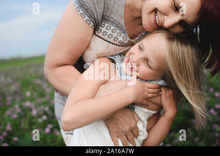 Gerne Großmutter umarmt Enkelin auf der Blumenwiese Stockfoto