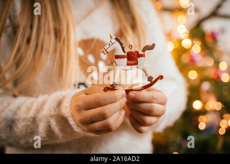 Schmücken den Weihnachtsbaum, Mädchen, dass einen dekorativen Metall Schaukelpferd Stockfoto