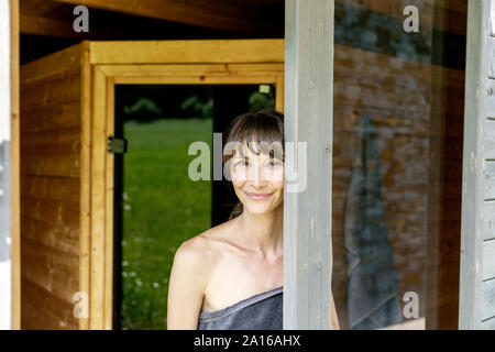 Portrait von lächelnden Frau hinter Fensterglas in der Sauna Stockfoto