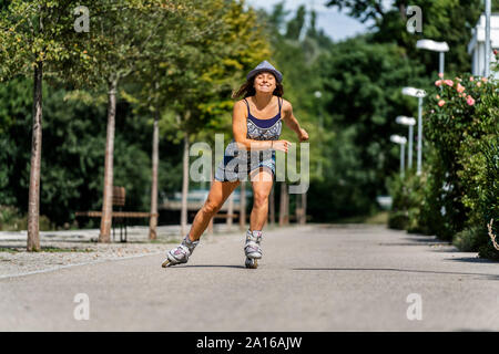 Lächelnden jungen Frau reiten Inline Skates Stockfoto