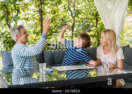 Gerne Vater und Sohn hohe Fiving, nachdem er ein Spiel auf der Terrasse Stockfoto