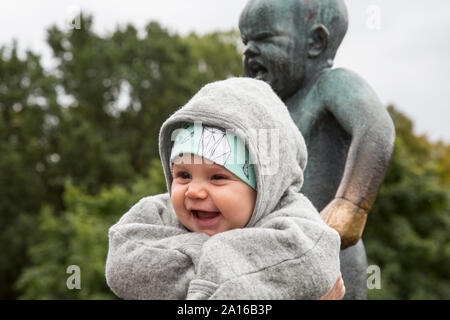 Lachendes Baby mit Statue von Baby schreien Stockfoto