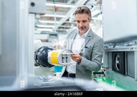 Geschäftsmann mit Tablette montageroboter in einer Fabrik Stockfoto