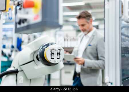 Geschäftsmann mit Tablette montageroboter in einer Fabrik Stockfoto