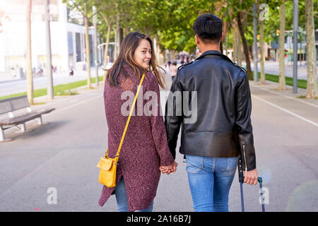 Touristen Paar Hände halten und auf der Straße mit einem Rad Koffer, Barcelona, Spanien Stockfoto