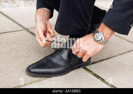 Geschäftsmann seinen Schuh auf Pflaster binden, close-up Stockfoto