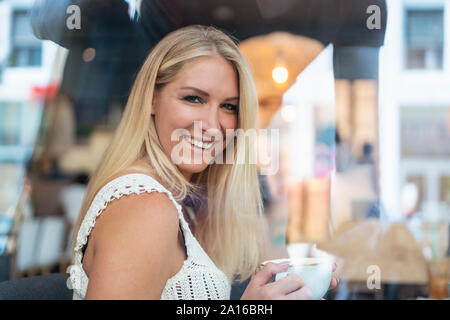 Portrait von lächelnden blonde Frau trinkt Kaffee in einem Cafe Stockfoto