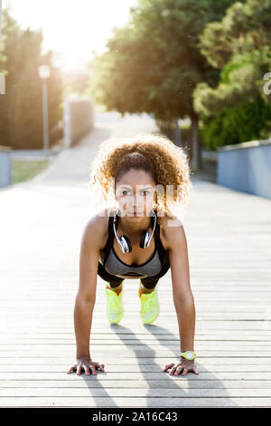 Sportliche Frau, Push-ups auf einer Brücke Stockfoto