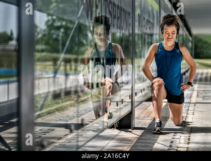 Junge sportliche Frau, Kopfhörer tragen und Stretching Übung Stockfoto