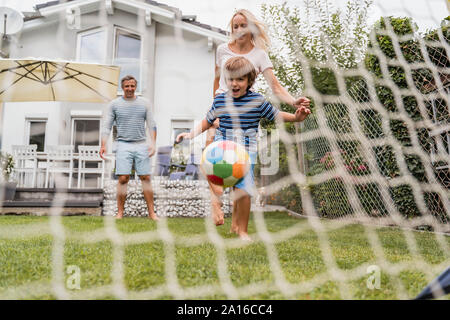 Glückliche Familie Fußball spielen im Garten Stockfoto