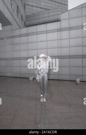 Mädchen in Silber Anzug lookinng durch VR-Brille Stockfoto