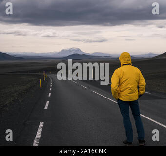 Mann stand auf leere Straße, im Abstand suchen, Island Stockfoto