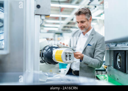 Geschäftsmann mit Tablette montageroboter in einer Fabrik Stockfoto