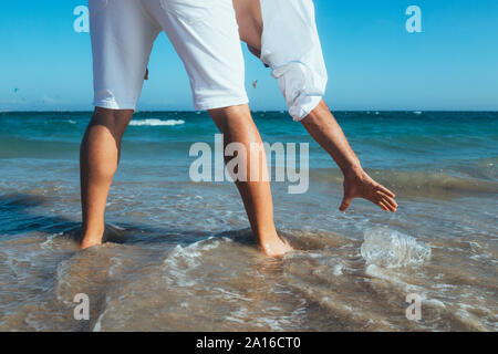 Mann, der an der Küste herauf leere Plastikflasche Stockfoto