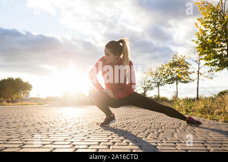 Junge Frau ihr Bein dehnen in einem Park Stockfoto
