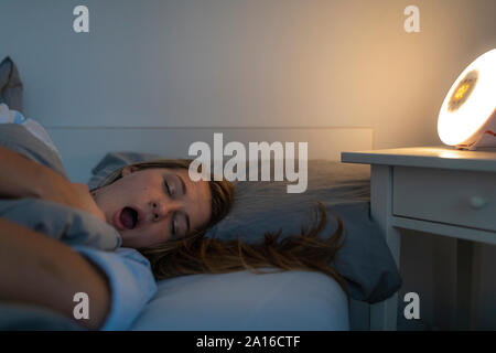 Junge Frau im Bett zu Hause liegen in der Nacht gähnen Stockfoto
