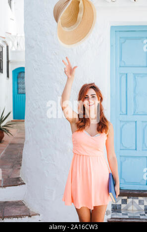 Porträt der rothaarige junge Frau warf ihren Strohhut in der Luft, Nerja, Malaga, Spanien Stockfoto