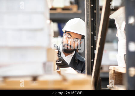 Junger Mann, der harte Hut Arbeiten in ein Lager Stockfoto