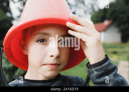 Porträt eines Jungen mit einem roten Eimer auf dem Kopf Stockfoto