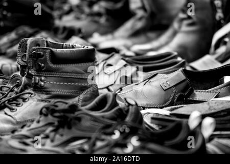 Ein schwarz-weiß Foto aus einer Sammlung von Ausgerichteten abgenutzte Schuhe; verschwommen Vorder- und Hintergrund. Stockfoto