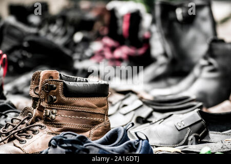 Paare von verschlissenen Schuhe mit ein paar klassischen alten Stiefel im Vordergrund; verschwommenen Hintergrund. Stockfoto