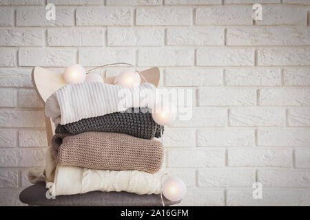 Stapel von warmen gestrickte Pullover auf dem Stuhl mit glühenden girlande an der Oberseite Stockfoto