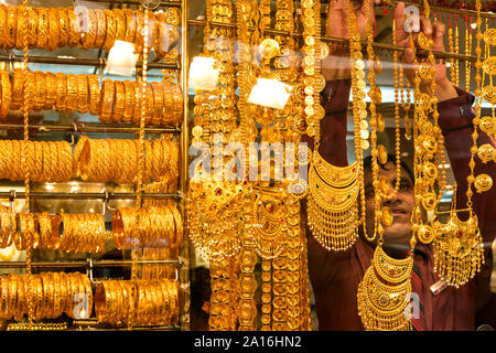 DUBAI - ein ladenbesitzer nimmt eine goldene Halskette aus seinem Fenster Anzeige im Gold Souk. Stockfoto