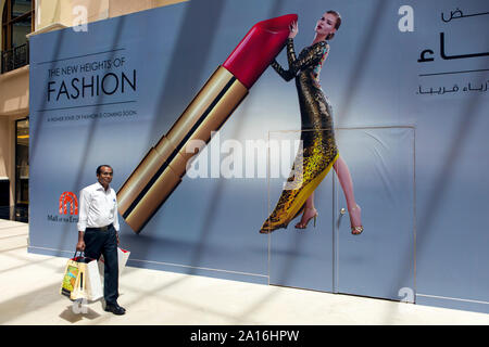 DUBAI - ein Mann, der einkaufstaschen vor einem Lippenstift Werbung innerhalb der Mall of the Emirates. Die reichen Scheichs, Shop hier oft senden Stockfoto