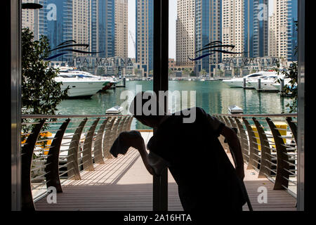 DUBAI - Silhouette eines Mannes Reinigung die Schiebetüren in Richtung Dubai Marina Yacht Club. Stockfoto