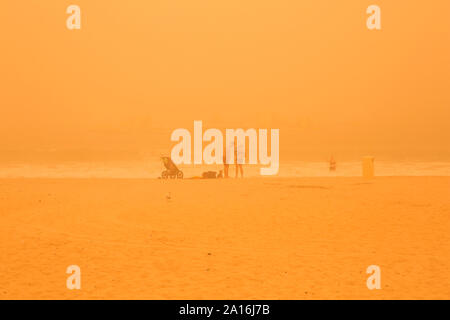 DUBAI - Touristen am Strand in Dubai Marina durch den Dunst der massiven Sandsturm, dass die Emirate am Donnerstag schlagen gesehen. Stockfoto