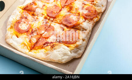 Peperroni Pizza in einem Karton auf einem blauen Hintergrund. Essen Lieferung Konzept. Nahaufnahme. Stockfoto