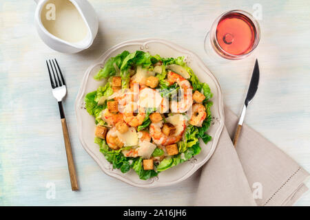 Garnelen Caesar Salat mit Parmesan Käse, Croutons und Salat, mit einem Glas Rose Wein und einer Soße Boot Stockfoto