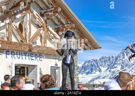 Künstler singt im Outdoor-Restaurant Apres mit schneebedecktem Blick auf den Mont-Blanc-Rücken an einem sonnigen Tag. La Folie Douce Saint Gervais von Chamonix. Stockfoto