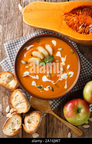 Kürbis Apfelmus Suppe mit Samen, Joghurt und Minze Nahaufnahme auf dem Tisch. Vertikal oben Ansicht von oben Stockfoto