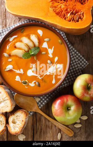 Äpfel Kürbispüree Suppe mit geröstetem Brot Nahaufnahme auf dem Tisch serviert. Vertikal oben Ansicht von oben Stockfoto