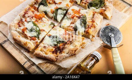 Pizza Margherita mit Basilikum auf einem Schneidebrett. Close-up. Horizontale erschossen. Orange Hintergrund Stockfoto