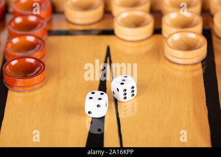 Würfel und Spielsteine auf einem hölzernen Spielbrett. Spiel Würfel werden auf der Oberfläche des Backgammon board wider. Close Up. Auf Würfel 4 3 Stockfoto