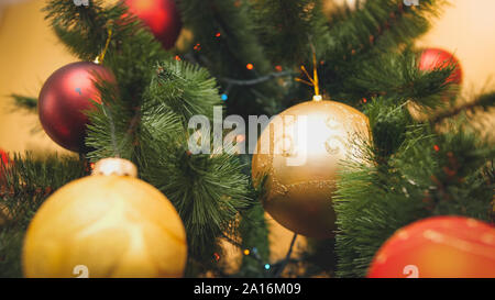 Closeup getonten Bild von rot und golden glitzernde Kugel hängen an Chrismtas Baum. Perfekte Zusammenfassung Hintergrund für den Winterurlaub oder Feiern Stockfoto