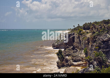 Tulum Küste mit türkisfarbenem Wasser, Strand, Palmen und Felsen. Stockfoto