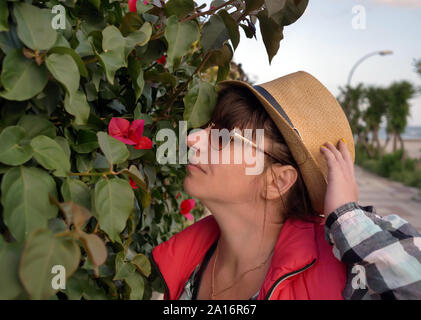 Attraktive junge Frau touristische rund um die Stadt Reisen genießen den Duft einer rosa Blume im Freien Stockfoto