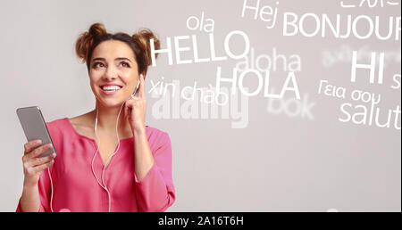 Frau mit Handy hören verschiedene Sprachen auf Grau Stockfoto