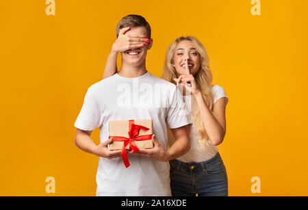 Lassen Sie sich überraschen. Mädchen die Augen ihres Freundes und stille Zeichen Stockfoto