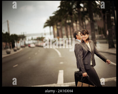 Mitte - Erwachsene Business woman Überqueren einer Straße mit einem männlichen Kollegen. Stockfoto