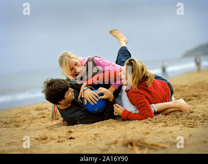 Eine Gruppe von Freunden über am Strand, während Sie über ein Fußball kämpfen. Stockfoto